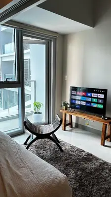 a living room with a flat screen tv and a table at Uptown Parksuites Tower Two - BGC Taguig, Manila in Manila
