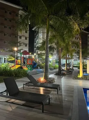 a courtyard with chairs and palm trees and a playground at Athena's Place - Hope Residences SMDC Trece Cavite in Trece Martires