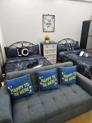 a living room with two beds and a couch with pillows at Athena's Place - Hope Residences SMDC Trece Cavite in Trece Martires