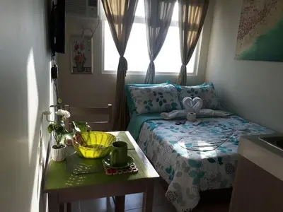 a bedroom with a bed with a table and a window at Para Sa'yo in Manila