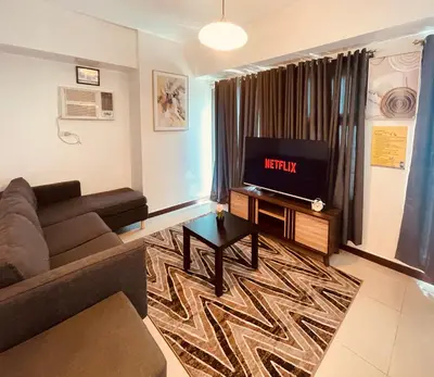 a living room with a couch and a flat screen tv at 1 Bedroom Homestay in 8 Adriatico Manila in Manila