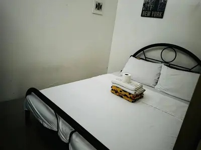 a white bed with a black frame and white pillows at Shore Residence D23 shortwalk MOA in Manila
