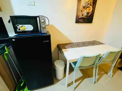 a microwave sitting on top of a refrigerator next to a table at Shore Residence D23 shortwalk MOA in Manila