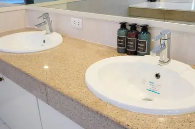 a bathroom counter with two sinks and two bottles of wine at Makati Altean Apartment (Delfin Room) in Manila