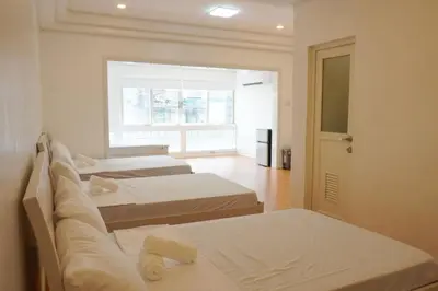a room with three beds and a window at Makati Altean Apartment (Maura Room) in Manila