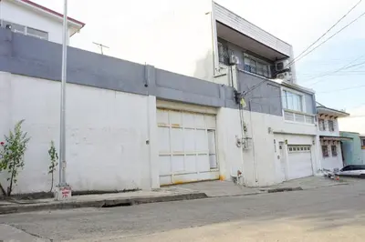 a white building with two garage doors on a street at Makati Altean Apartment (Maura Room) in Manila