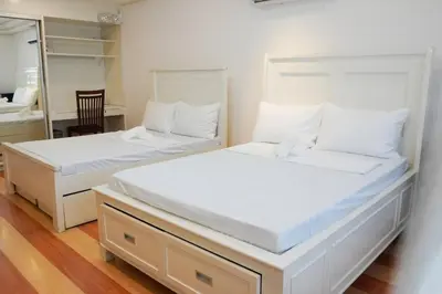 two white beds in a room with a mirror at Makati Altean Apartment (Leonora Room) in Manila