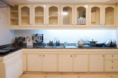 a kitchen with white cabinets and black counter tops at Makati Altean Apartment (Leonora Room) in Manila