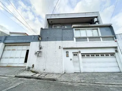 a white house with two garage doors on a street at Makati Altean Apartment (Leonora Room) in Manila