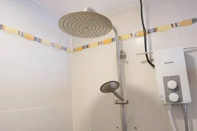 a shower with a shower head in a bathroom at Makati Altean Apartment (Leonora Room) in Manila