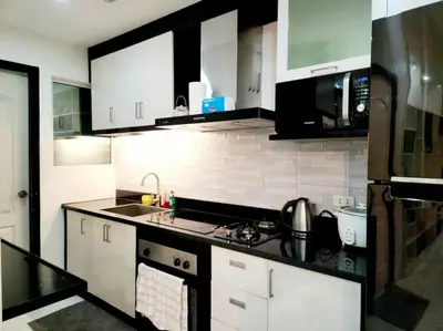 a kitchen with white cabinets and a black counter top at Alpha Grandview Malate Condo 2005 in Manila