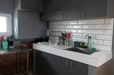 a kitchen with black cabinets and a sink at Maria Deck Urban Glamping in Manila