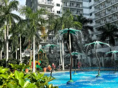 a swimming pool with a fountain with palm trees at Pasay City MOA, Pearl Suite in Shell Residences in Manila