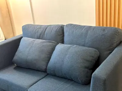 a blue couch with three pillows on it at Pasay City MOA, Pearl Suite in Shell Residences in Manila