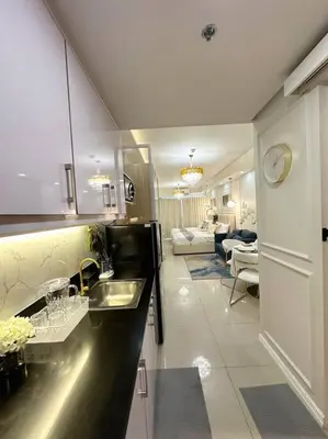 a kitchen with a sink and a living room at Pasay City MOA, Pearl Suite in Shell Residences in Manila