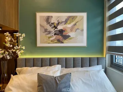 a bedroom with a bed with a painting above it at SMDC Fame Residence luxurious family suite condo near mrt in Manila