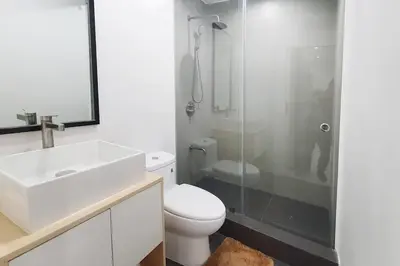 a bathroom with a toilet and a sink and a shower at Travelers Inn - Cozy Capsule Bunks, Makati in Manila