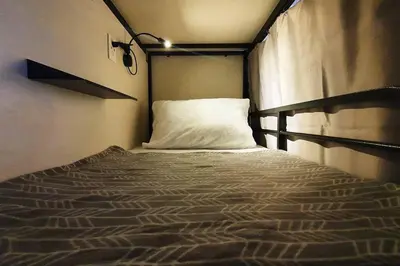 a bed with a white pillow in a room at Travelers Inn - Cozy Capsule Bunks, Makati in Manila
