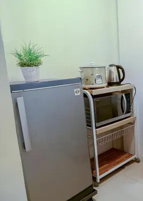 a refrigerator in a kitchen with a microwave on a cart at House of Citiflora Unit B in Manila