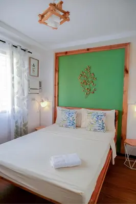 a bedroom with a large bed with a green wall at House of Citiflora Unit B in Manila