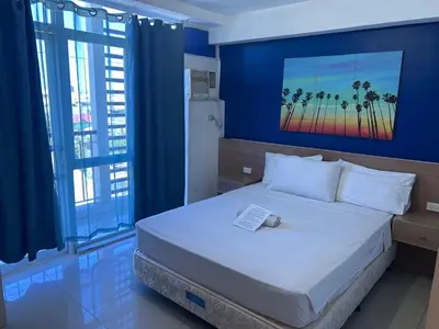 a bedroom with a large bed with a blue wall at Melbourne makati in Manila