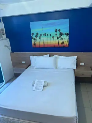 a bedroom with a white bed with a picture of palm trees at Melbourne makati in Manila