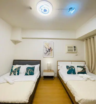 two beds in a room with a room with at 8 Adriatico - 1 Bedroom with 1 Parking Space near SLMEC, PGH and US Embassy in Manila