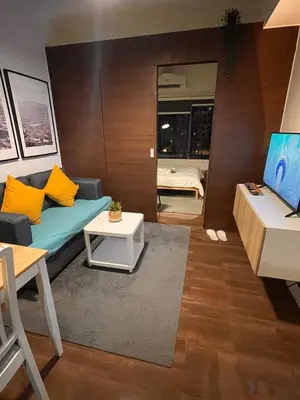 a living room with a blue couch and yellow pillows at Destina @Air Residences Makati, Metro Manila in Manila