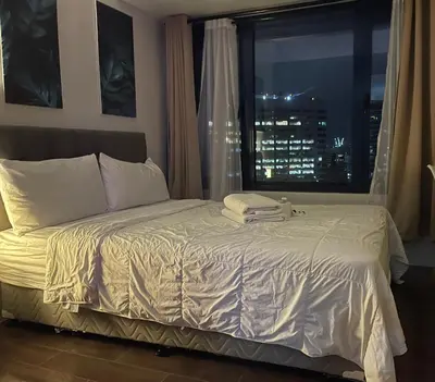 a bedroom with a bed with a window with a city skyline at Destina @Air Residences Makati, Metro Manila in Manila