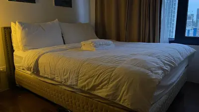 a bed with white sheets and pillows and a window at Destina @Air Residences Makati, Metro Manila in Manila