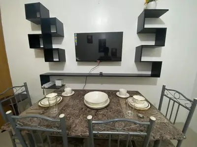 a dining room with a table with chairs and a television at YUYANS Staycation Shell Residences in Manila