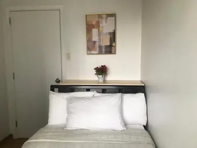 a bed with white pillows and a vase of flowers on top at Simple Yet Lovely 2BR Unit in Acqua Private Residences in Manila