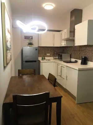 a kitchen with a wooden table and white cabinets at Simple Yet Lovely 2BR Unit in Acqua Private Residences in Manila