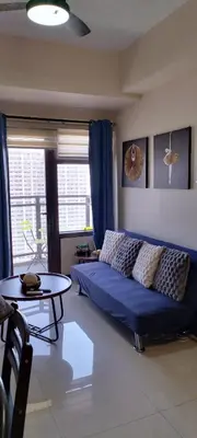 a living room with a blue couch and a table at Sundawn RadianceManilaBay in Manila