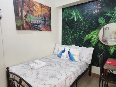 a bed in a room with a painting on the wall at DG CONDOTEL @MANHATTAN PLAZA T2 STUDIO WITH BALCONY , 50 INCH TV AND UNLI WIFI @Araneta Cubao Quezon City Philippines in Manila