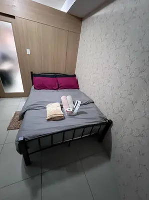 a bedroom with a bed with two towels on it at JAL's Cozy Haven in Manila
