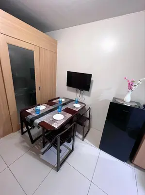 a room with a table with chairs and a television at JAL's Cozy Haven in Manila