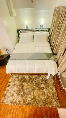 a bed in a bedroom with a rug on the floor at Modern Condo for Couple with Wi-Fi, Netflix & Kitchen, 1 min to MRT Boni in Manila