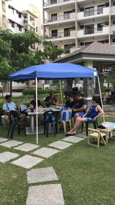 a group of people sitting at a table under a blue umbrella at 3BR Resort Style Condo in Manila