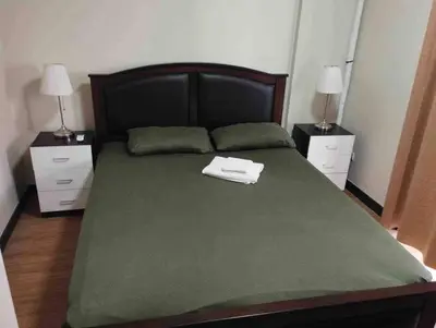 a large bed with a green blanket and two night stands at 3BR Resort Style Condo in Manila
