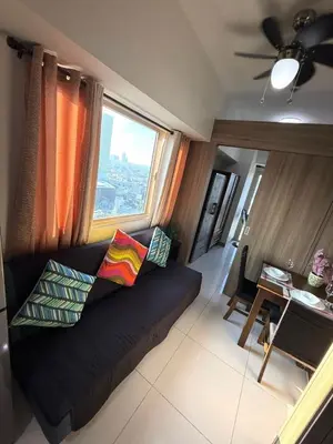 a living room with a black couch and a window at Cozy Two Bedroom Family Suites at Coast Residences near PICC, WTC & MOA in Manila