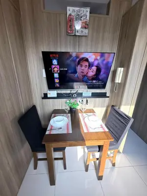 a dining room with a table and a flat screen tv at Cozy Two Bedroom Family Suites at Coast Residences near PICC, WTC & MOA in Manila