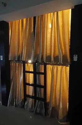 a window with a ladder in front of a curtain at C Place - Capsule B - Upper in Manila