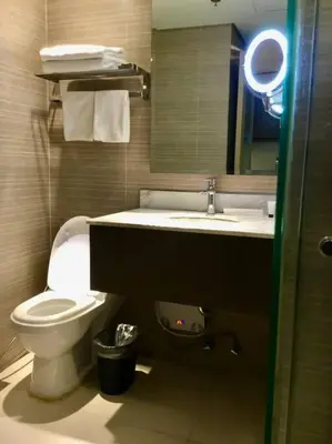 a bathroom with a toilet and a sink and a mirror at Cozy 1 Studio Room - The Residences BGC Taguig in Manila