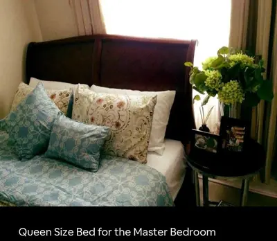 a bed with pillows and a vase of flowers on a table at Elegant 2BR Condo unit with free WiFi in Anabu Primero