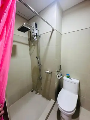 a bathroom with a toilet and a shower with a pink curtain at Serendipity Suite at S Residences in Manila