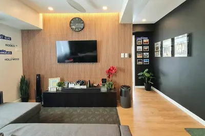 a room with a tv on a wall with a clock at California Themed Condo in BGC in Manila