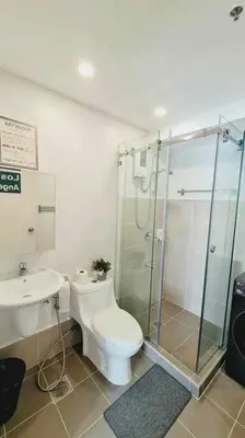 a bathroom with a toilet and a glass shower at California Themed Condo in BGC in Manila