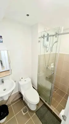 a bathroom with a shower and a toilet and a sink at California Themed Condo in BGC in Manila