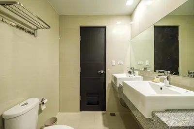 a bathroom with a sink and a toilet and a mirror at Premium 3BR Suite UptownBGC w/ Bathtub & Balcony in Manila